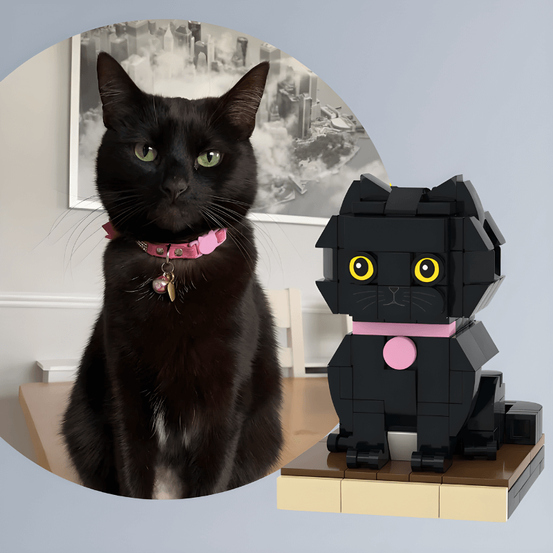 Real black cat with a pink collar next to a black cat figurine on a wooden surface.