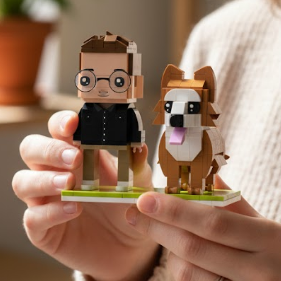 Two custom brick figures, one resembling a person with glasses and the other a dog, on a green base held by a person.