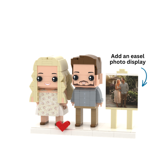 Custom block figure couple set with a blonde woman in a floral dress, a brown-haired man in a blue shirt, a red heart, and a small easel displaying a photo of the couple, on a white background.