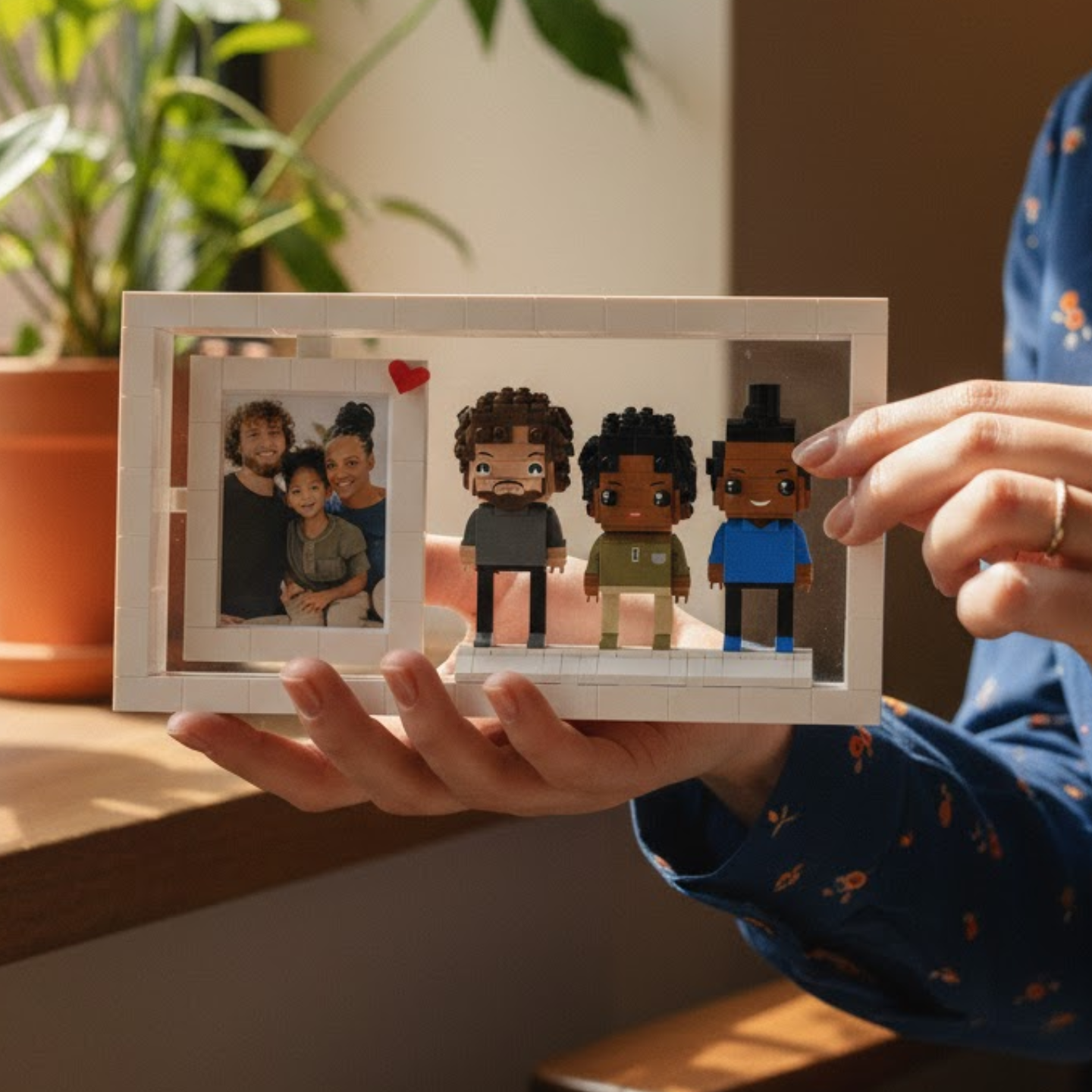 Person holding a LeGO brick frame with mini figures and a photo of a family.