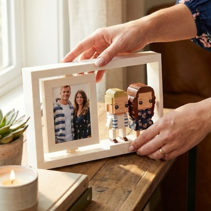 Person holding lego brick frame with photos and custom mini figurines on a wooden surface.