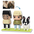 Custom brick figures set showing three assembled figures: a man with glasses and black hair, a woman in an olive green jacket and beige hat, and a black and white French Bulldog. An arrow points from a small photo of a couple and dog at the top left to the assembled figures below, on a white background.