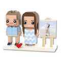 Custom couple brick figure set featuring a couple of personalized character figures and an easel with a photo print, on a white display base with a red heart accent, isolated on a white background.