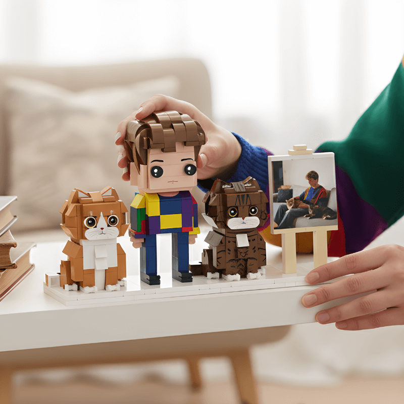 Person holding a LEGO set with a owner and two dogs on a table.