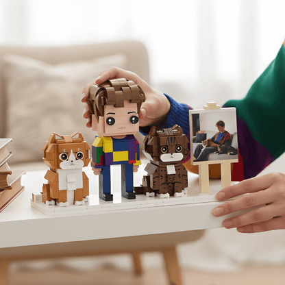 Person holding a LEGO set with a owner and two dogs on a table.