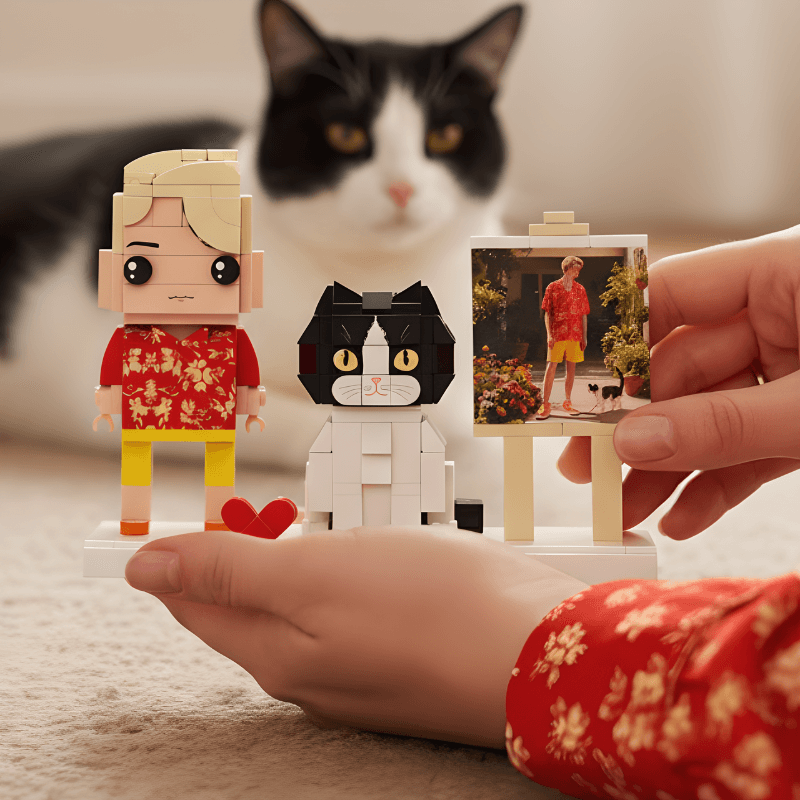 Person holding a custom mini figure with a cat-themed figure and a person in a red shirt, with a black and white cat in the background.