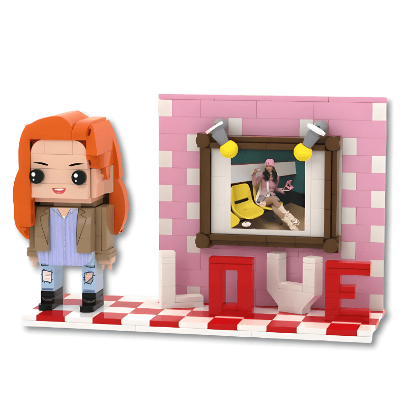 Toy figure of a person with orange hair next to a pink wall with a framed picture and 'LOVE' letters.