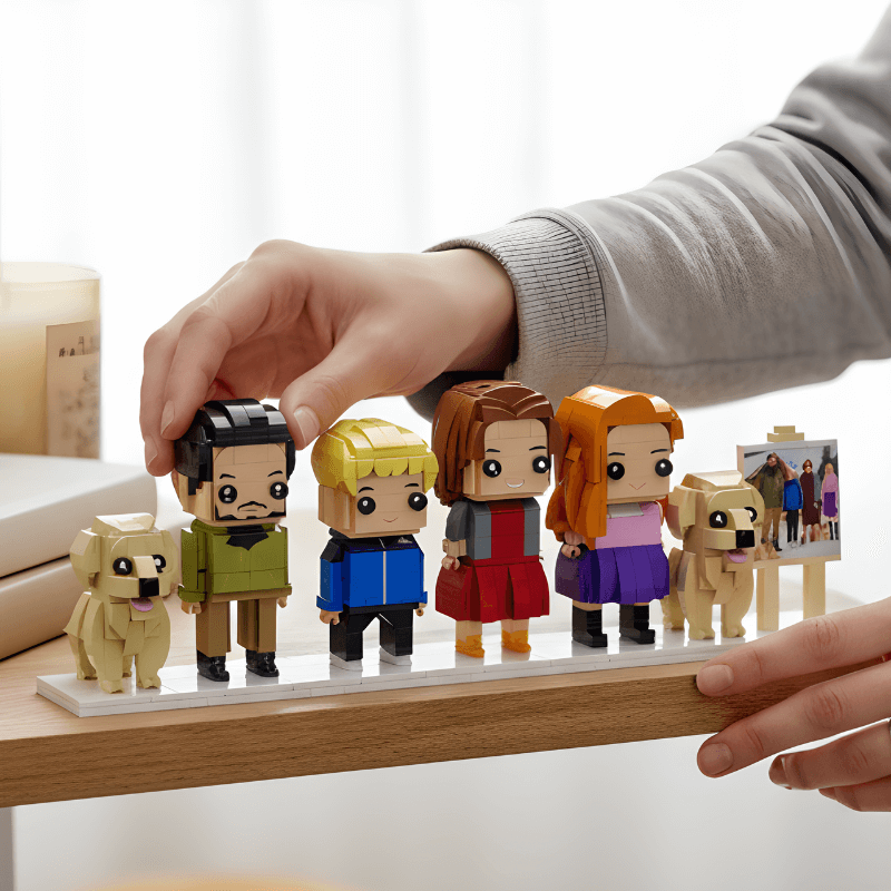 Set of personalized mini figures resembling people and dogs on a wooden stand with a hand interacting with them.