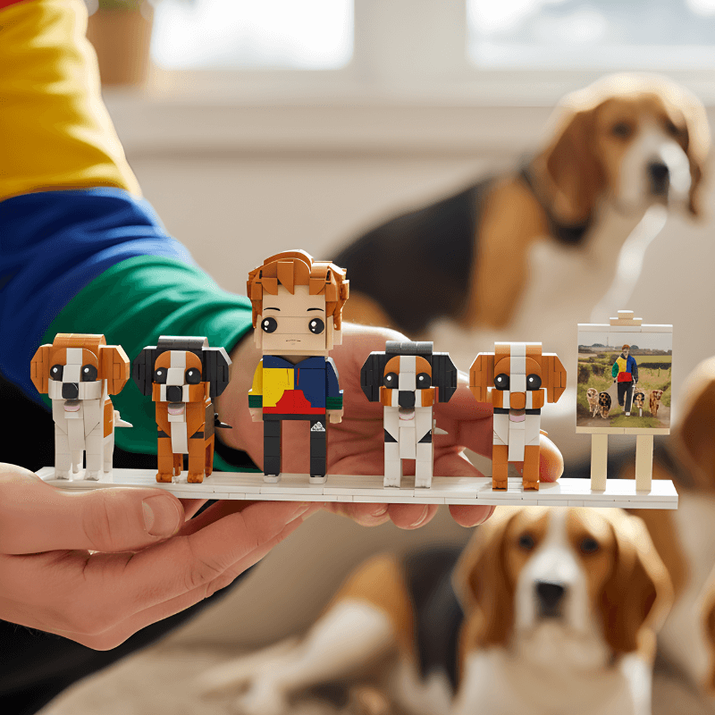 Hand holding a set of custom mini figures with dogs and a person, with a dog in the background.